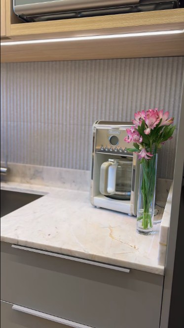 Bancada de cozinha em mármore com cafeteira e flores