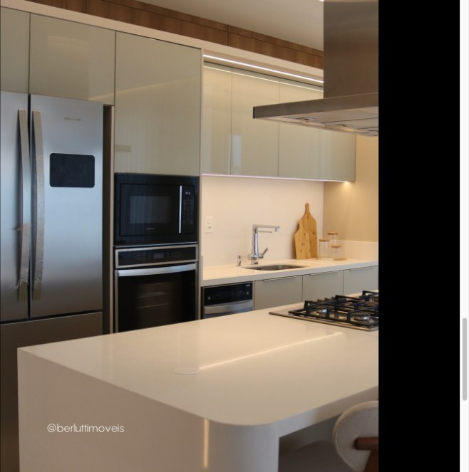 Cozinha branca com ilha, cooktop e torre de eletrodomésticos embutidos