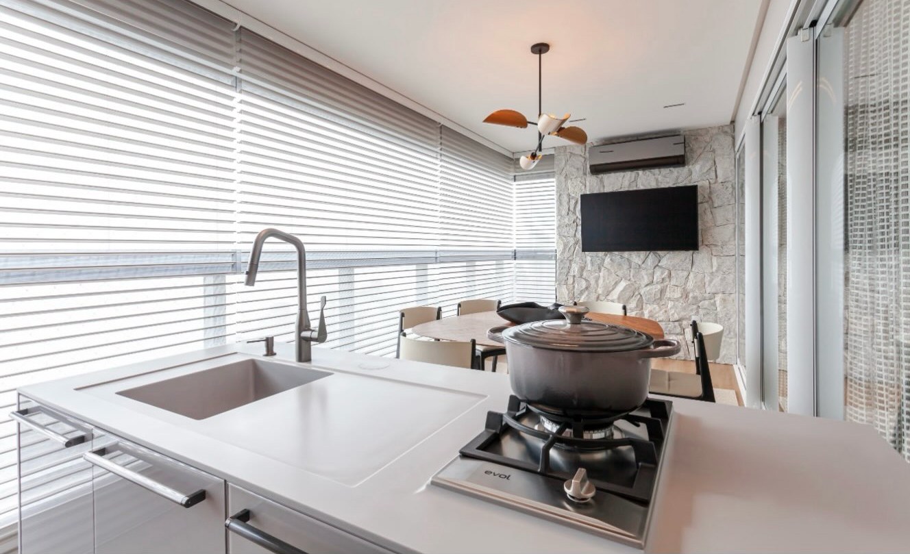 Varanda gourmet com bancada monolítica, cooktop e cuba integrada