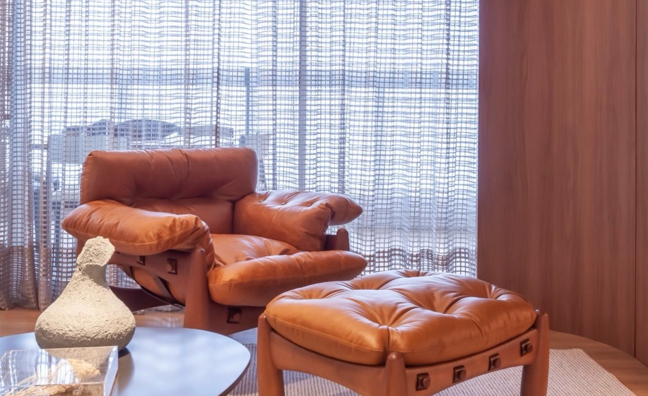 Living com marcenaria curva em madeira nobre e poltrona de couro